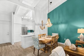 A modern kitchen with white cabinetry, a stainless steel refrigerator, and a teal accent wall. - Steps to the Beach Pool Courts Family Fun (Destin)