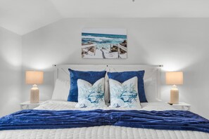 A bedroom with a bed, two bedside lamps, a headboard, and a wall-mounted picture. - Steps to the Beach Pool Courts Family Fun (Destin)