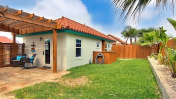 Una casa de un solo piso con techo de tejas, un porche cubierto y un patio trasero cercado.