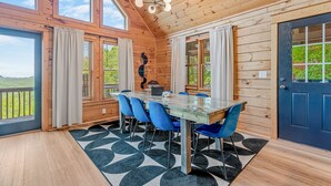 A wooden interior with a dining table, chairs, and a view of greenery outside. - The Summit in Mars Hill (Mars Hill)
