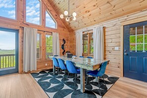 A wooden interior with a dining table, chairs, and a view of greenery outside. - The Summit in Mars Hill (Mars Hill)