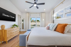 A bedroom with a bed, a ceiling fan, a TV, a dresser, and a view of the outdoors. - Sports Court Playground Putt Putt Spa Pool (Bradenton)