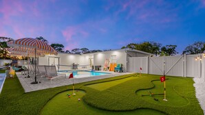 A backyard with a swimming pool, a putting green, and a covered seating area. - Sports Court Playground Putt Putt Spa Pool (Bradenton)