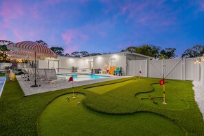 A backyard with a swimming pool, a putting green, and a covered seating area. - Sports Court Playground Putt Putt Spa Pool (Bradenton)