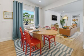 Un comedor con una mesa redonda, sillas rojas y vistas al exterior a través de una ventana.