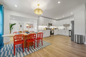 A modern kitchen with white cabinets, a central island with red chairs, and a hanging light fixture. - Sports Court Playground Putt Putt Spa Pool (Bradenton)