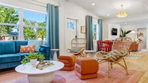 A modern living room with a blue sofa, wicker chairs, a coffee table, and a view of the outdoors. - Sports Court Playground Putt Putt Spa Pool (Bradenton)