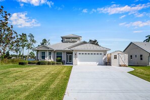 A two-story house with a garage, a covered porch, and a small shed. - Luxury Lakefront Private Dock Pool In-ground Spa (Lake Placid)