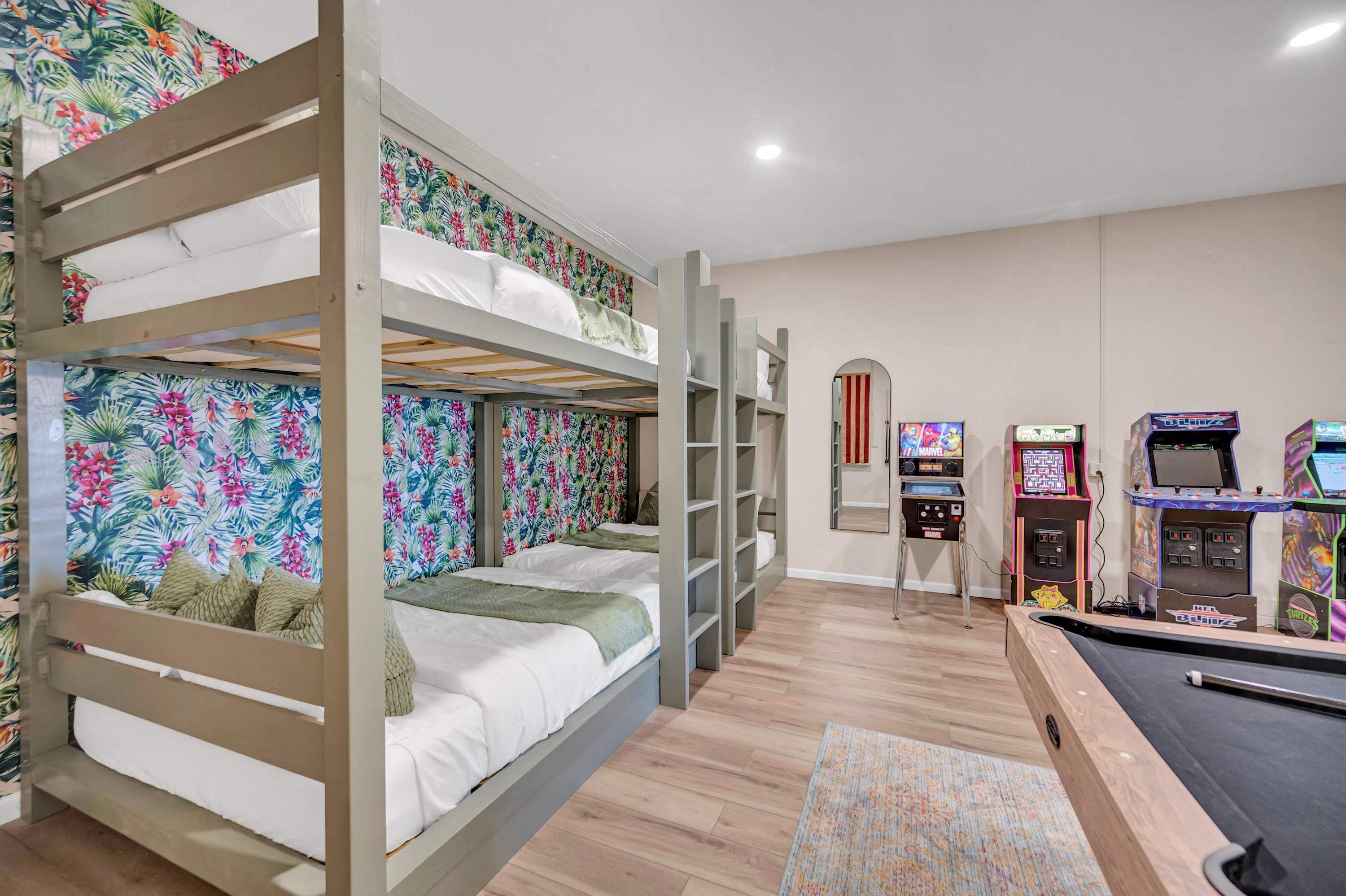 A room with bunk beds, a pool table, and arcade games.