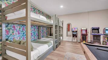 A room with bunk beds, a pool table, and arcade games.