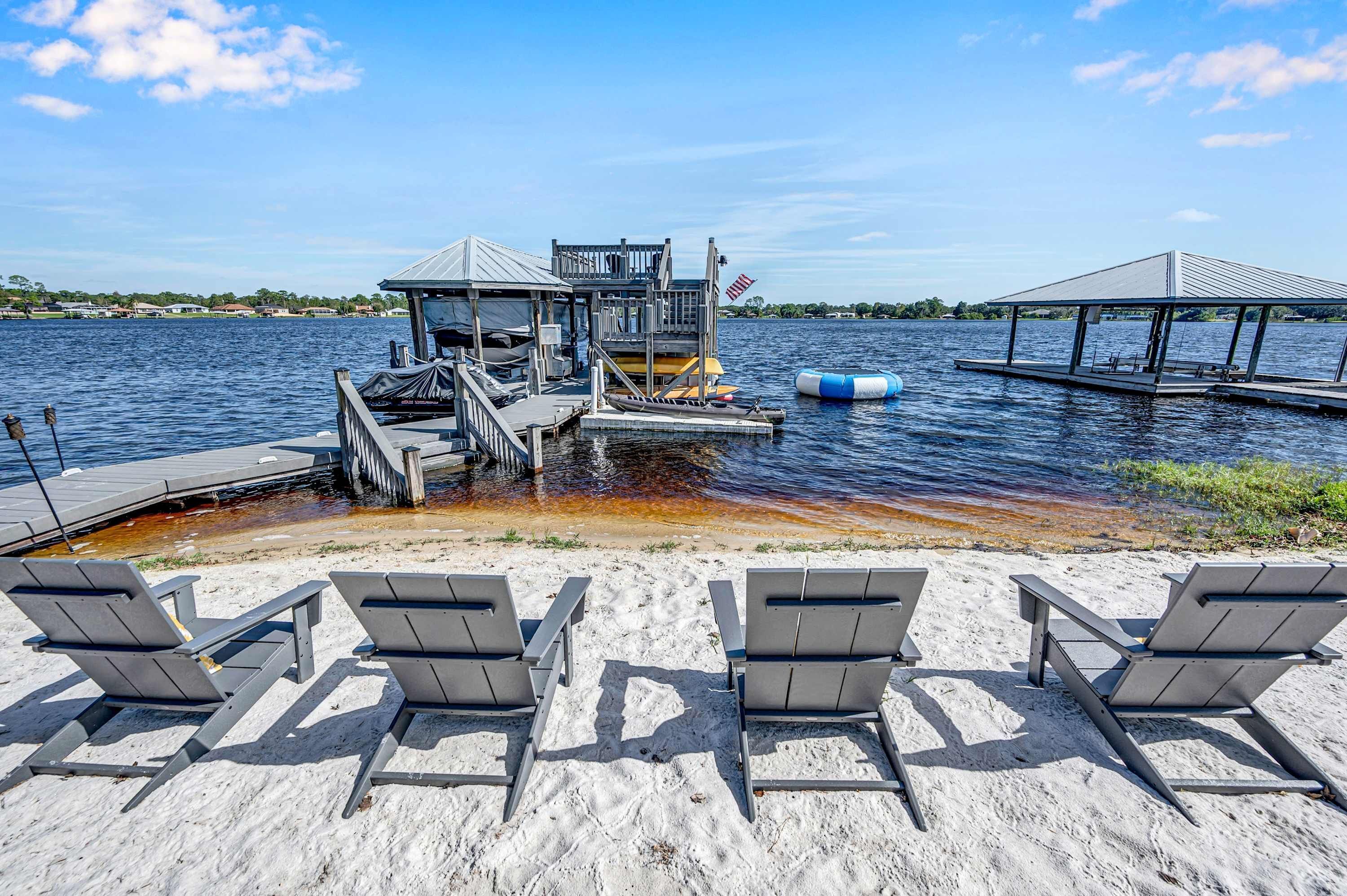 A waterfront property with a dock, lounge chairs, and a small pavilion.