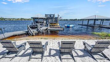 A waterfront property with a dock, lounge chairs, and a small pavilion.