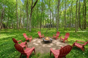 A circular seating arrangement around a central fire pit in a forested area. - Pocono Escape Fire Pit Game Room Lake Access (East Stroudsburg)