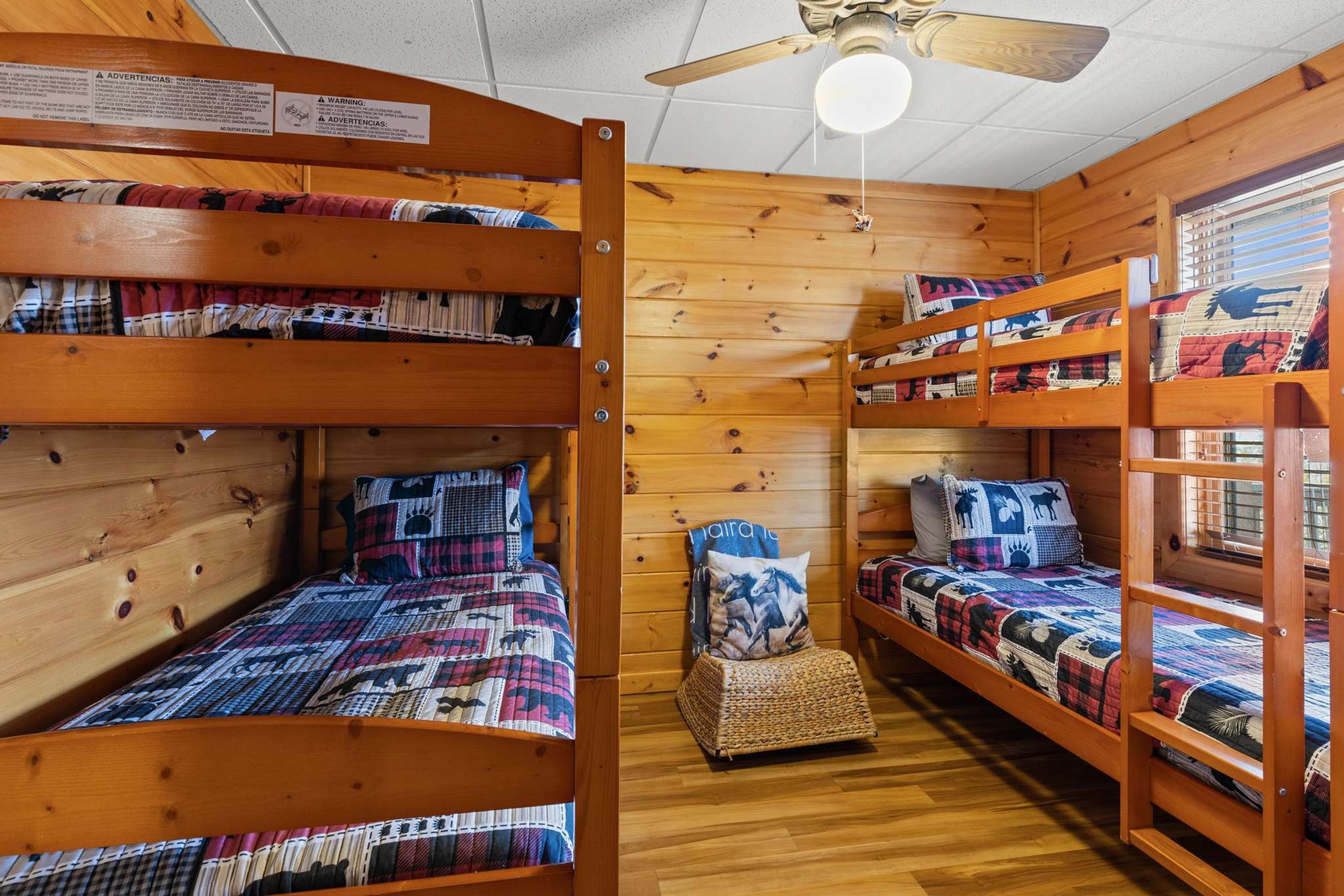 Une cabine avec des lits superposés, des murs en bois, un ventilateur de plafond et une fenêtre.