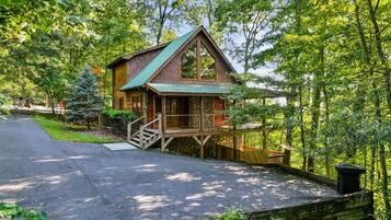 Une cabane en bois avec un toit en pente, une terrasse en bois et des fondations en pierres.