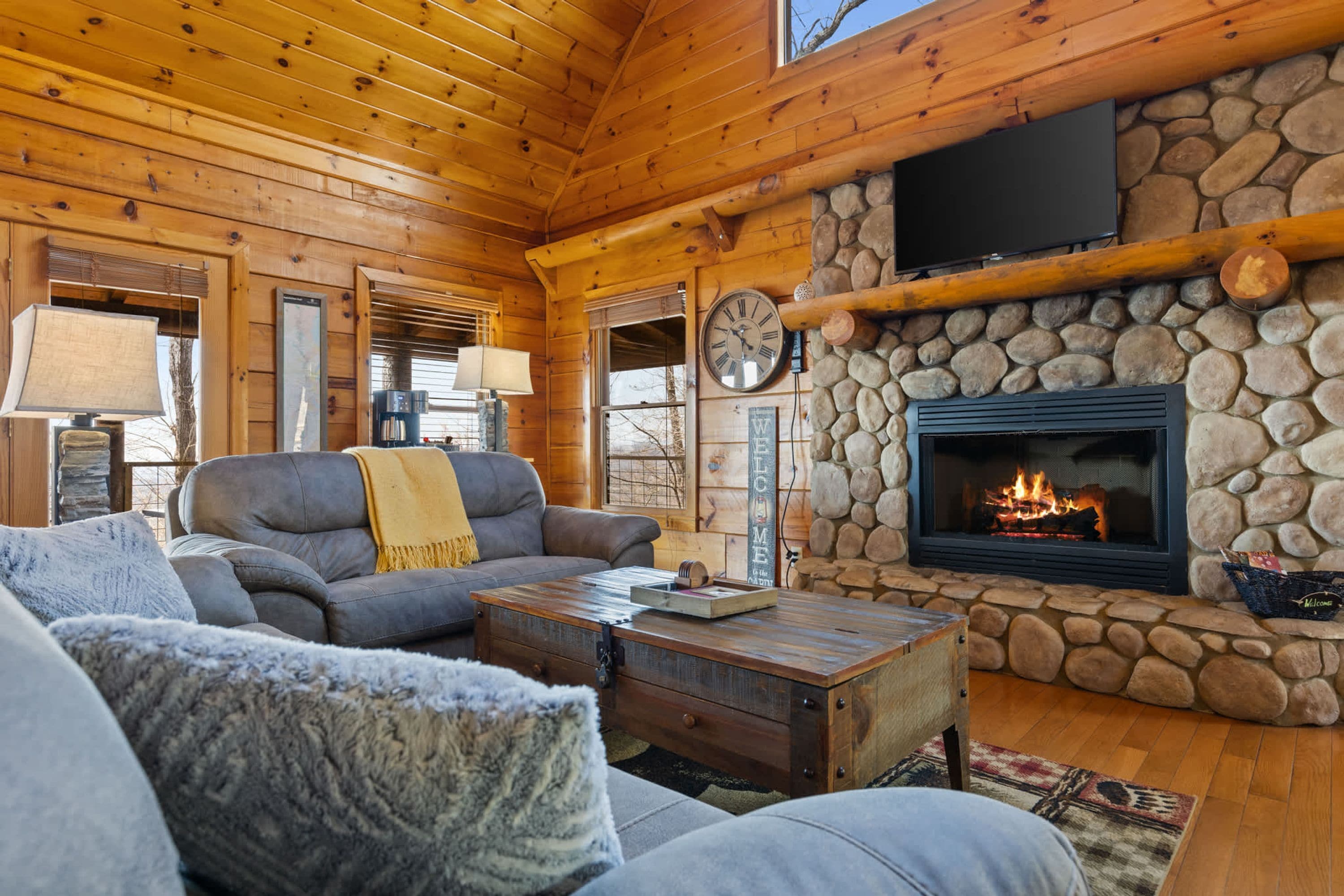 L’intérieur chaleureux d’un chalet avec une cheminée en pierre, des murs en bois et un coin salon confortable.