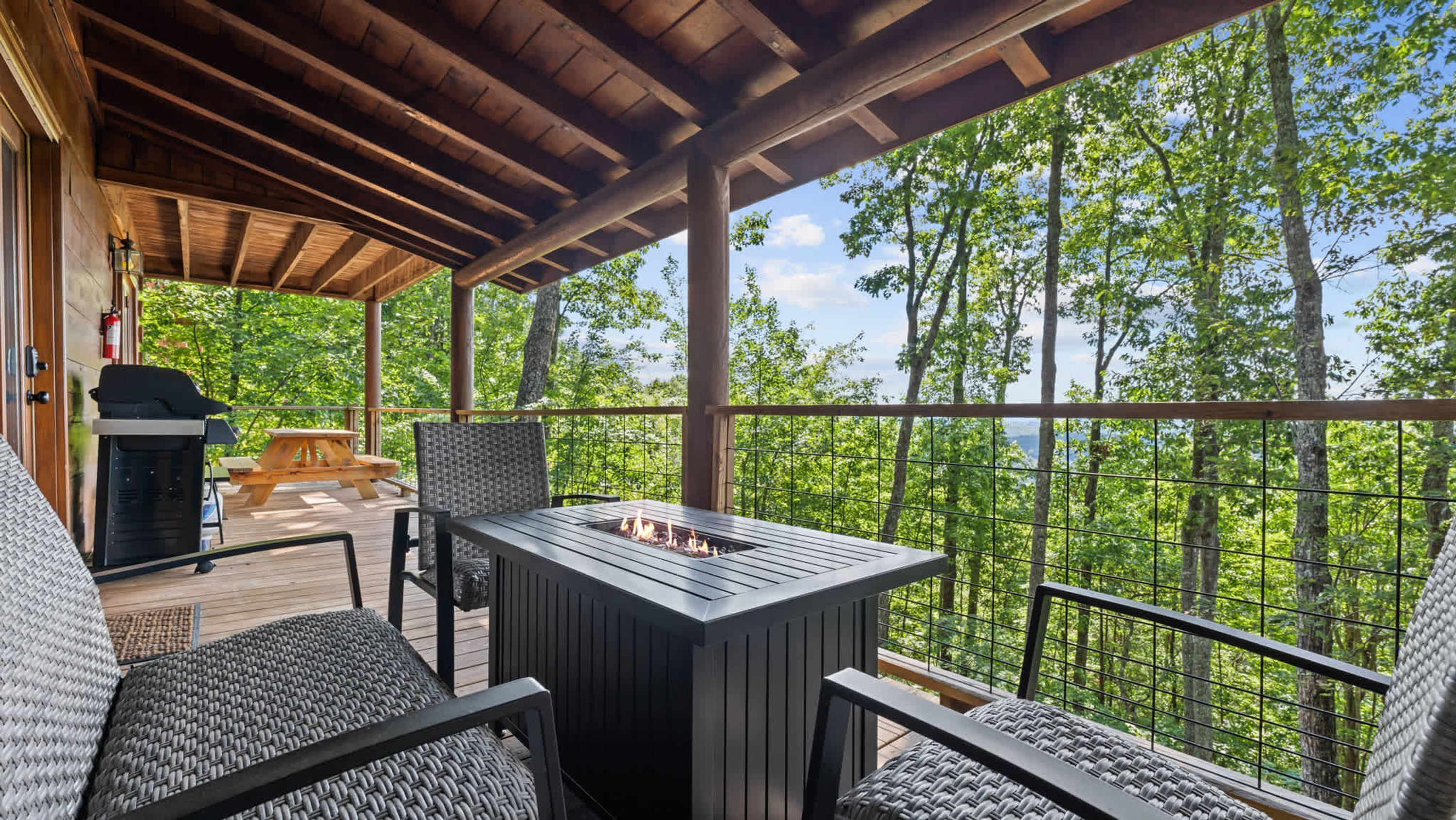 An outdoor deck with a grill, seating, and a fire pit.