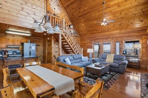 Ein geräumiges Cabin-Interieur mit Essbereich, Wohnzimmer, Küche und einer Treppe, die in ein Obergeschoss führt.