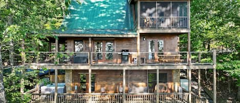 Eine mehrstöckige Holzhütte mit einem Balkon, Sitzgelegenheiten im Freien und einem überdachten Bereich.