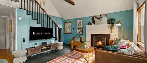 A living room with a fireplace, a television, and a staircase.