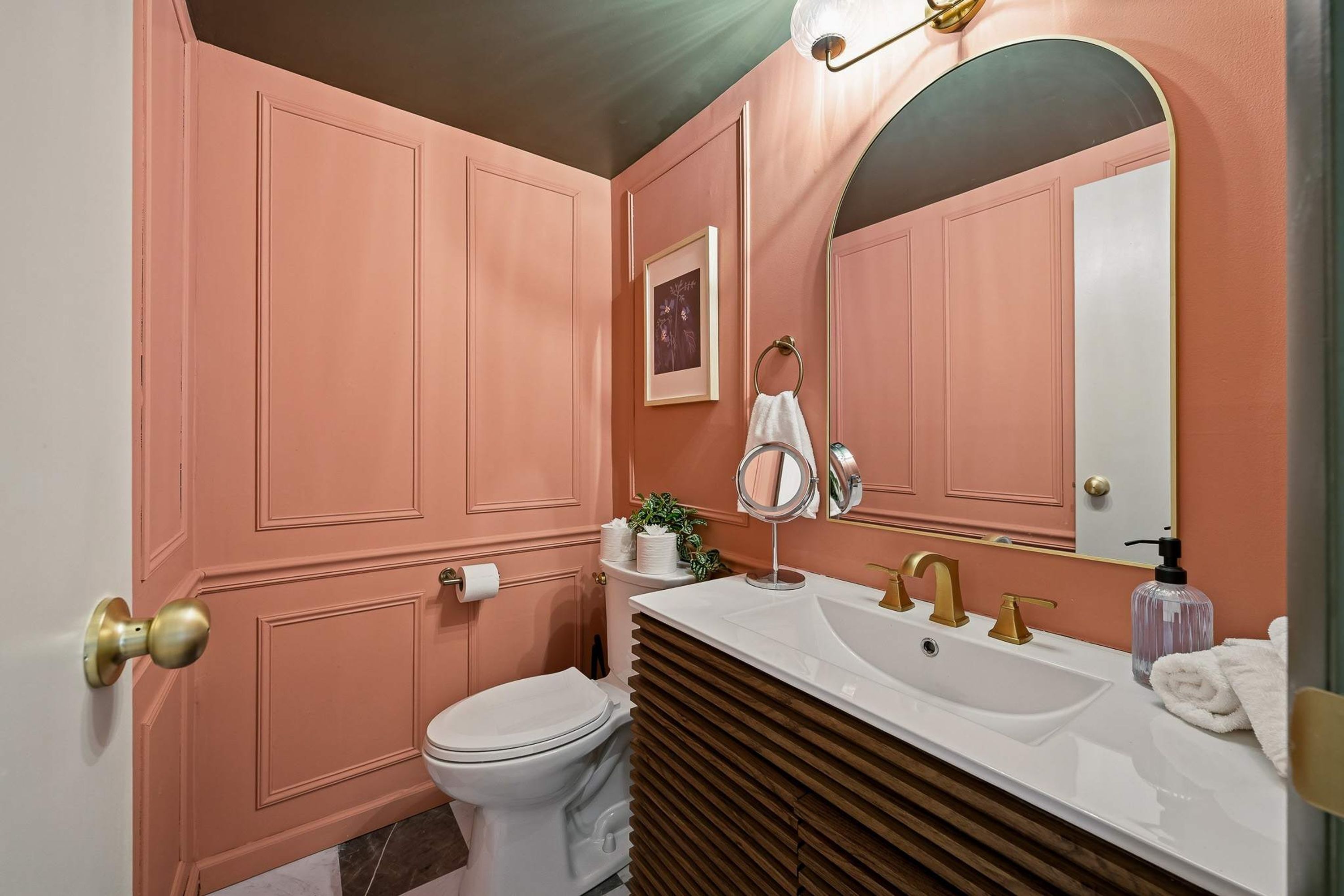 Une salle de bain avec des toilettes blanches, un meuble-lavabo avec un miroir et un évier.