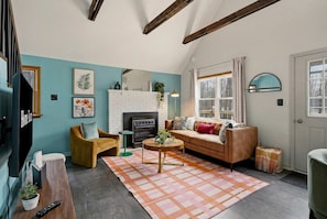 A cozy living room with a fireplace, a sofa, a coffee table, and a television.