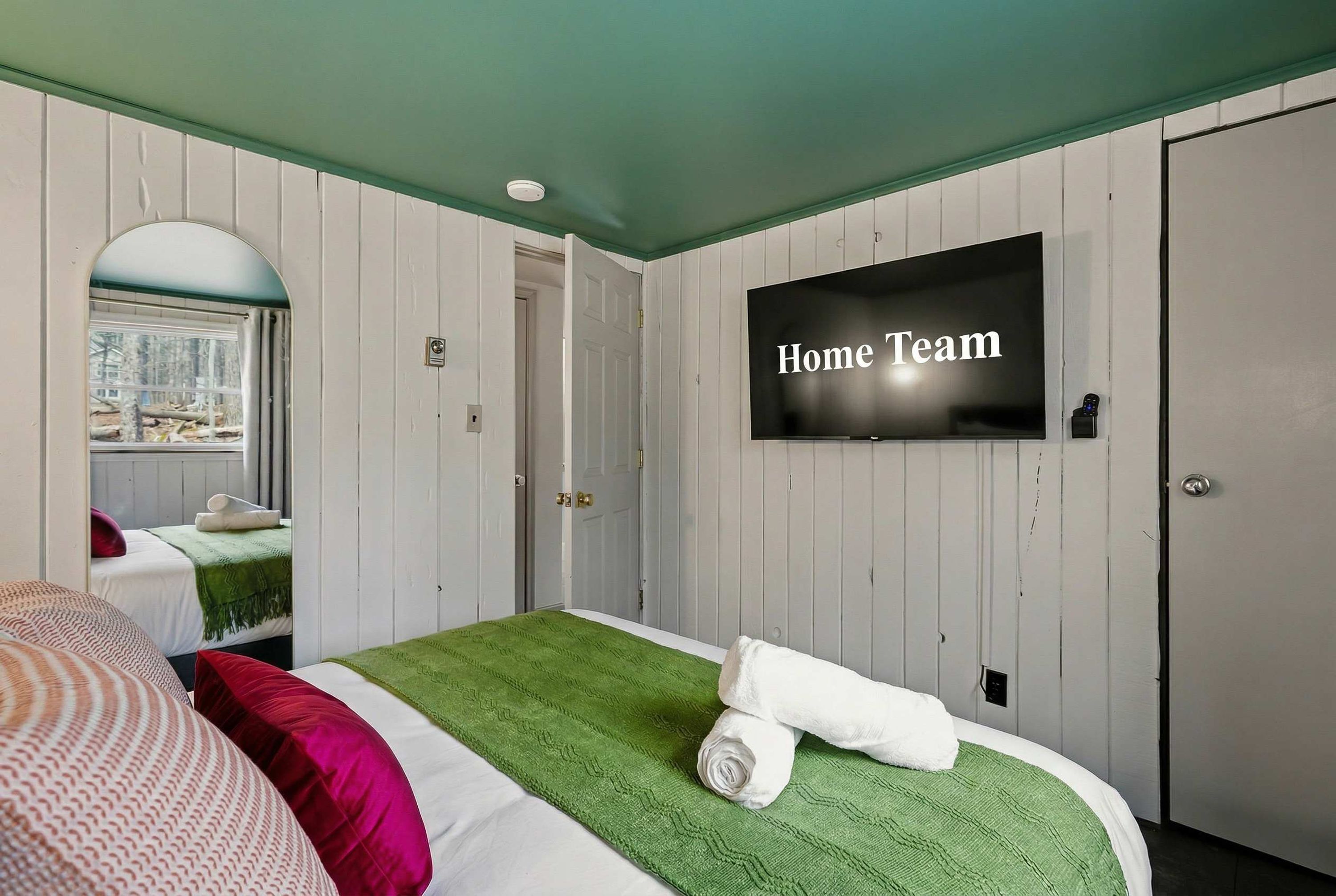 A hotel room with a bed, a television, and a door.