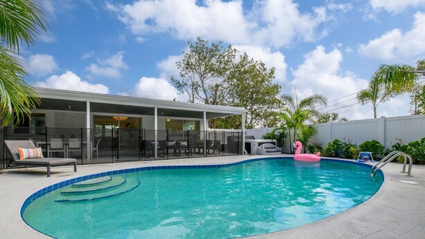 A swimming pool with a covered patio area, lounge chairs, and a pink flamingo float. - Breezy Blue-pool Hot Tub Minutes to Beach Games (Largo)