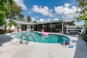 Ein Swimmingpool mit einem rosa Flamingo-Schwimmpfad, einer überdachten Terrasse und einem Grillbereich.