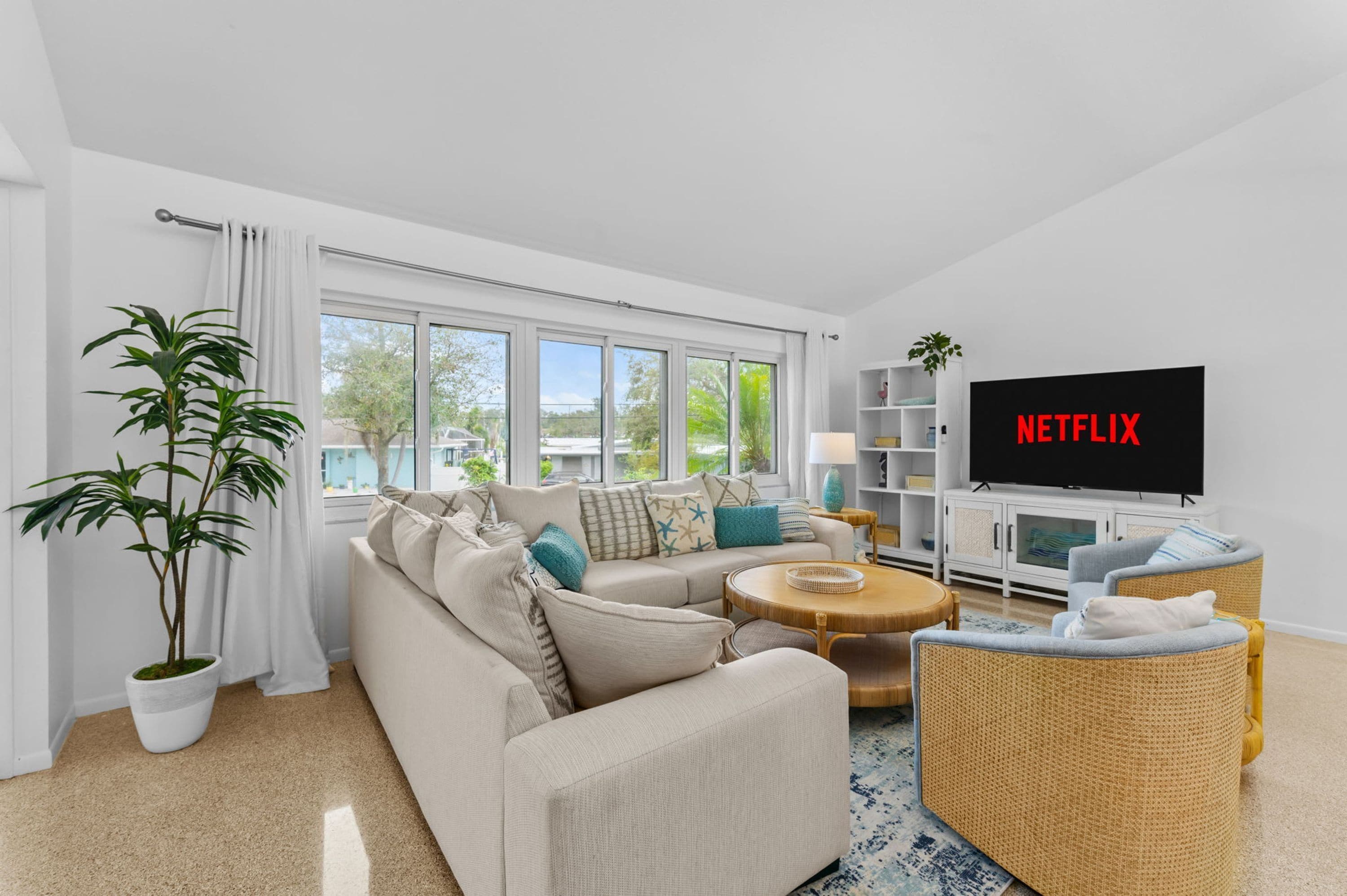 Una sala de estar moderna con sofá, mesa de centro y un televisor de pantalla plana mostrando 'NETFLIX'.