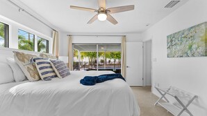 A bedroom with a bed, a ceiling fan, a view of the outdoors, and a painting on the wall. - Breezy Blue-pool Hot Tub Minutes to Beach Games (Largo)