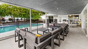 A covered outdoor area with a pool, seating, and a view of a house. - Breezy Blue-pool Hot Tub Minutes to Beach Games (Largo)