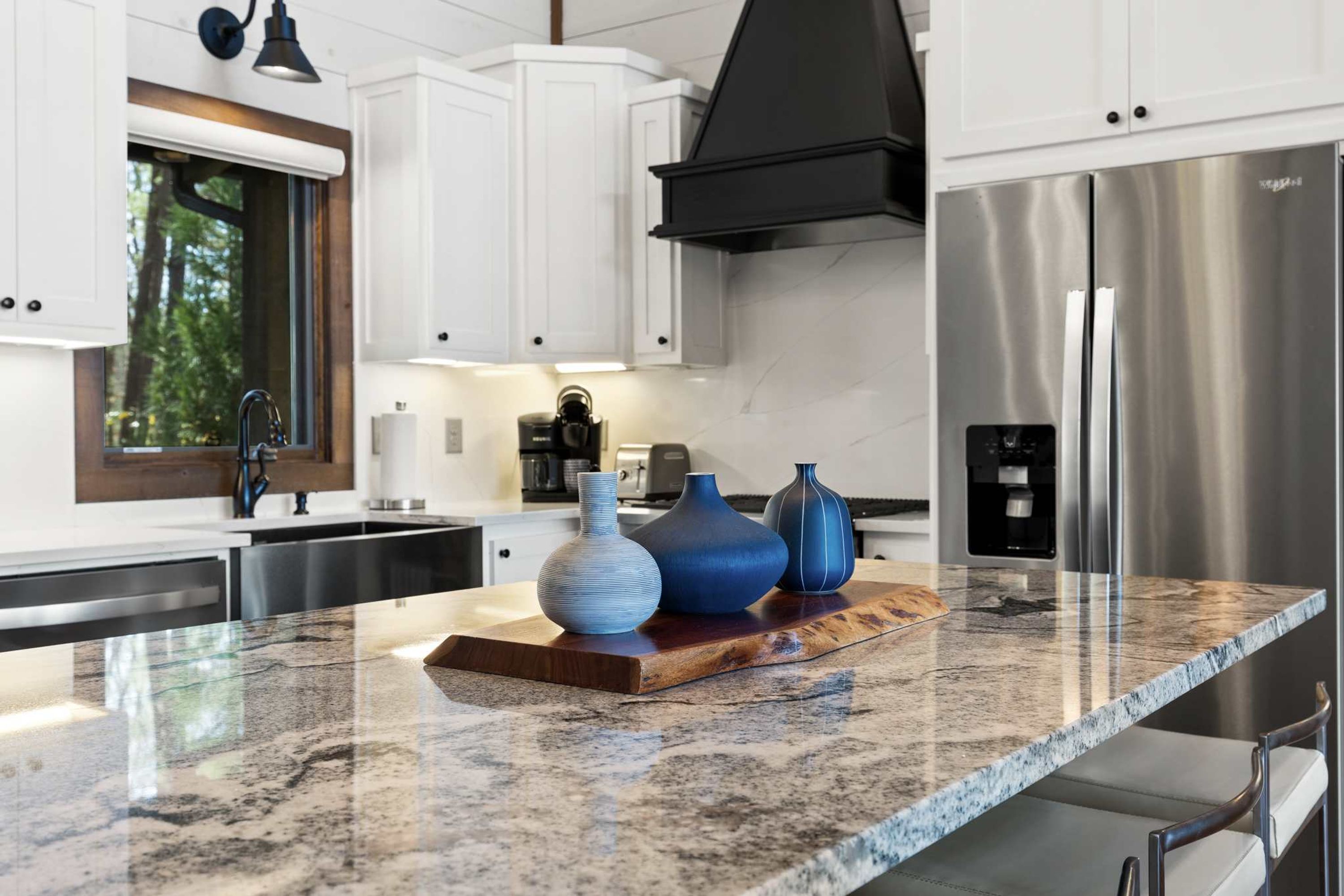 Una cocina con gabinetes blancos, un refrigerador de acero inoxidable y una encimera de granito.