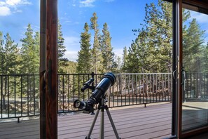 A telescope on a deck with a railing, overlooking a forested area. - 34 Acre Escape Games Hiking Pool Table Bicycles (Black Hawk)