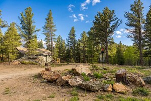 A rustic cabin with a dirt path leading to it, surrounded by a forest with tall pine trees. - 34 Acre Escape Games Hiking Pool Table Bicycles (Black Hawk)