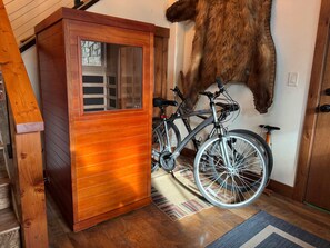 Ein Holzkabinett mit Glastür, ein angebrachtes Fahrrad und ein aufgestelltes Fellstück.