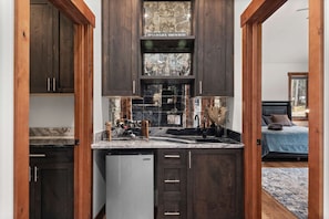 A compact kitchen with dark wood cabinets, a marble backsplash, and a dishwasher. - 34 Acre Escape Games Hiking Pool Table Bicycles (Black Hawk)