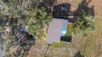 Vista aérea de una propiedad con una casa grande, piscina y árboles circundantes.