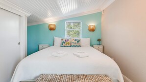 Una camera da letto con un letto, due comodini, una finestra con persiane e un soffitto a listelli di legno.
