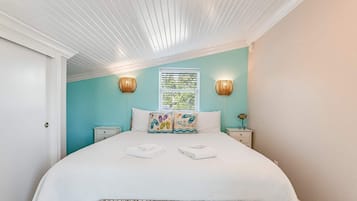Une chambre à coucher comprenant un lit, deux tables de chevet, une fenêtre avec des stores et un plafond avec des lambris en bois.