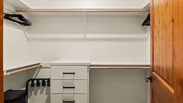 A walk-in closet with a wooden door, a white storage unit with drawers, and a shoe rack.