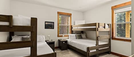 A bedroom with bunk beds, a window with a view, a nightstand, and a framed picture on the wall.