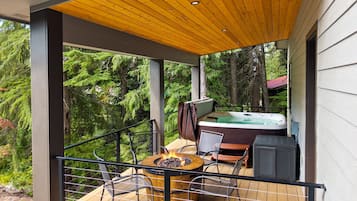 A balcony with a hot tub, a fire pit, and outdoor furniture.