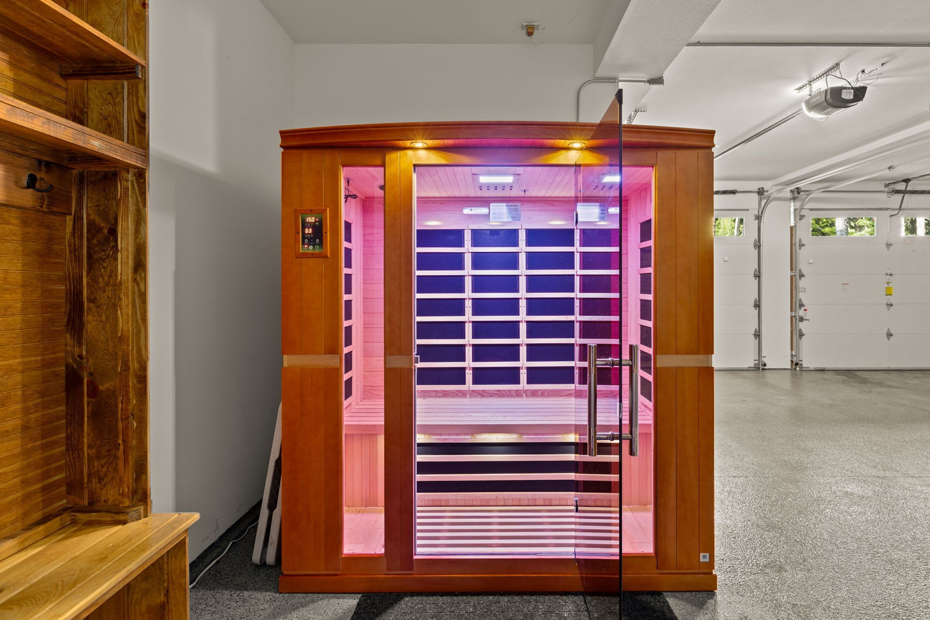 A sauna with a wooden exterior, a glass door, and a control panel on the wall.
