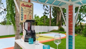 A cocktail lounge area with a blender, glasses, and a sign. - Resort Style Backyard Pickleball Pool Putt Putt (Seminole)