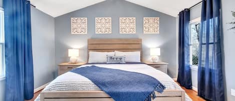 Une chambre à coucher avec un lit en bois, deux tables de chevet, un ventilateur de plafond et des panneaux décoratifs sur les murs.