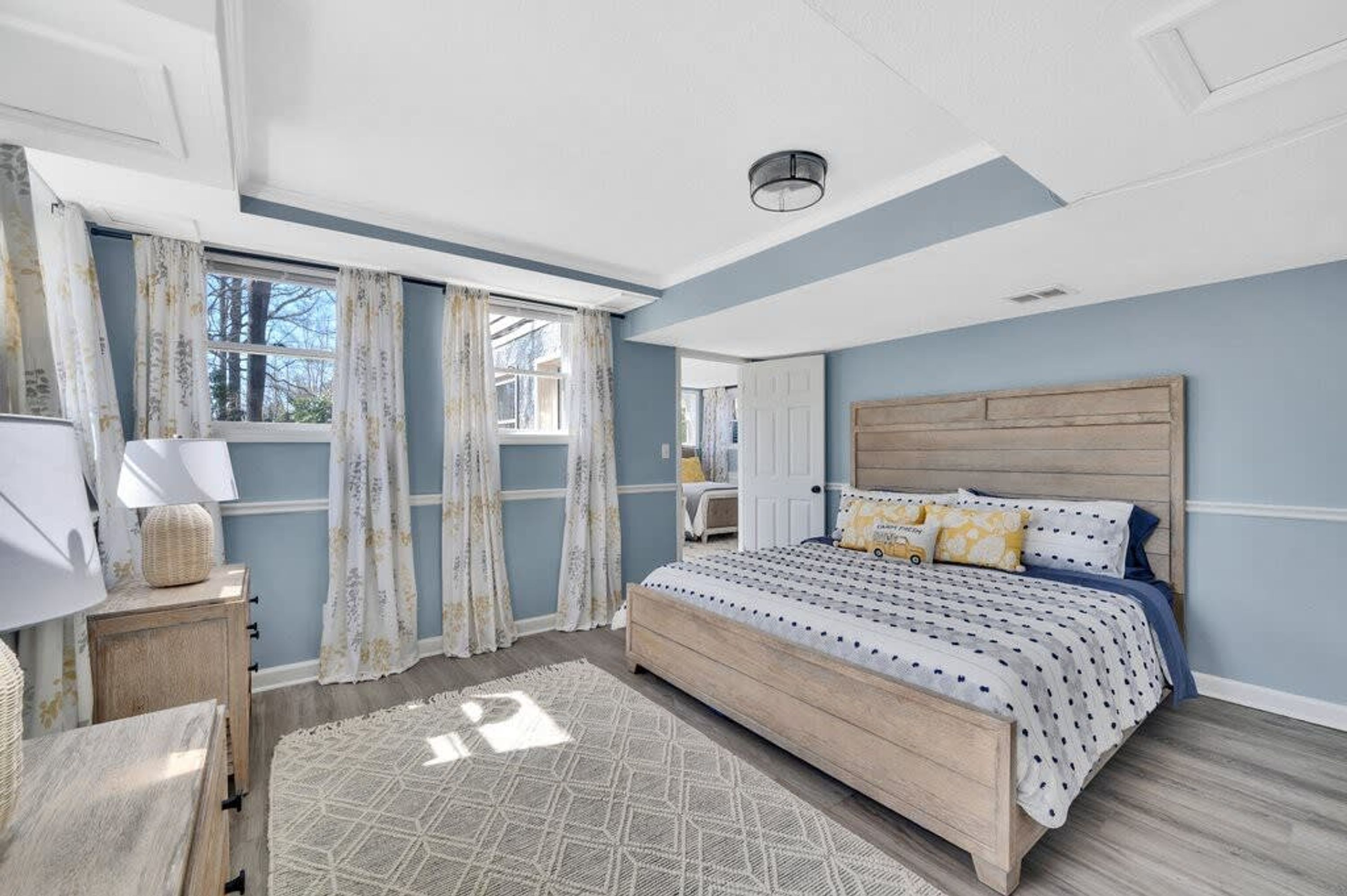 A bedroom with a bed, curtains, a bedside table, and a window.