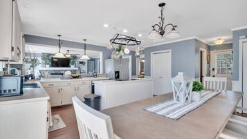 A modern kitchen with white cabinetry, a central island, pendant lighting, and a view to the outside.