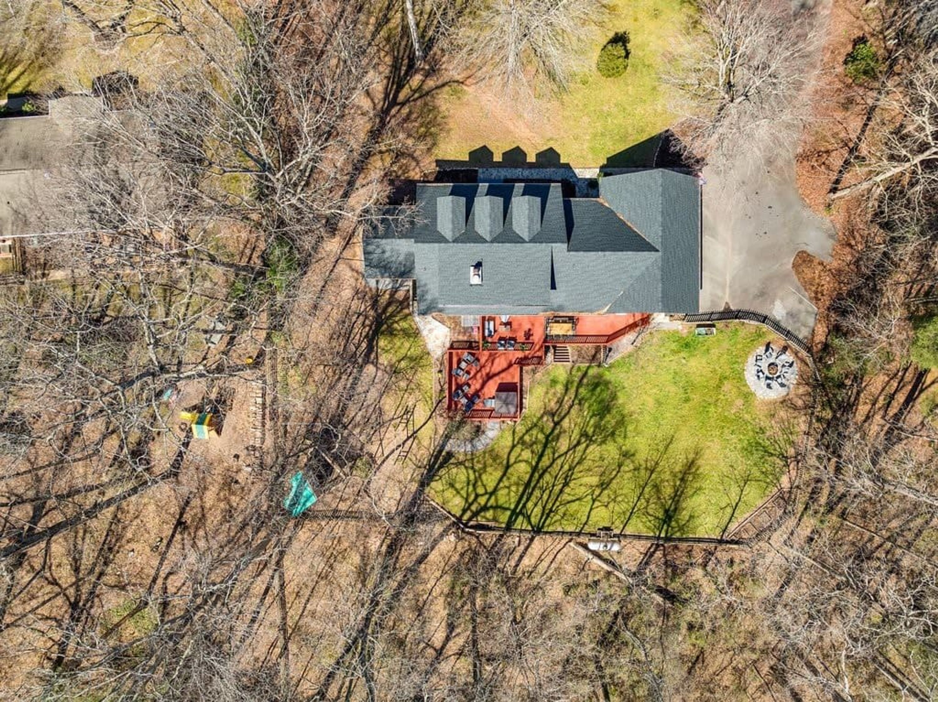 A house with a large front yard, a circular driveway, and a fenced area.