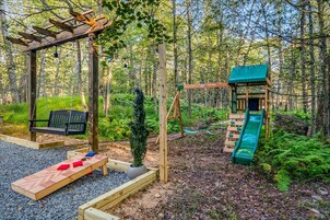 A playground with a swing set, slide, and bench.